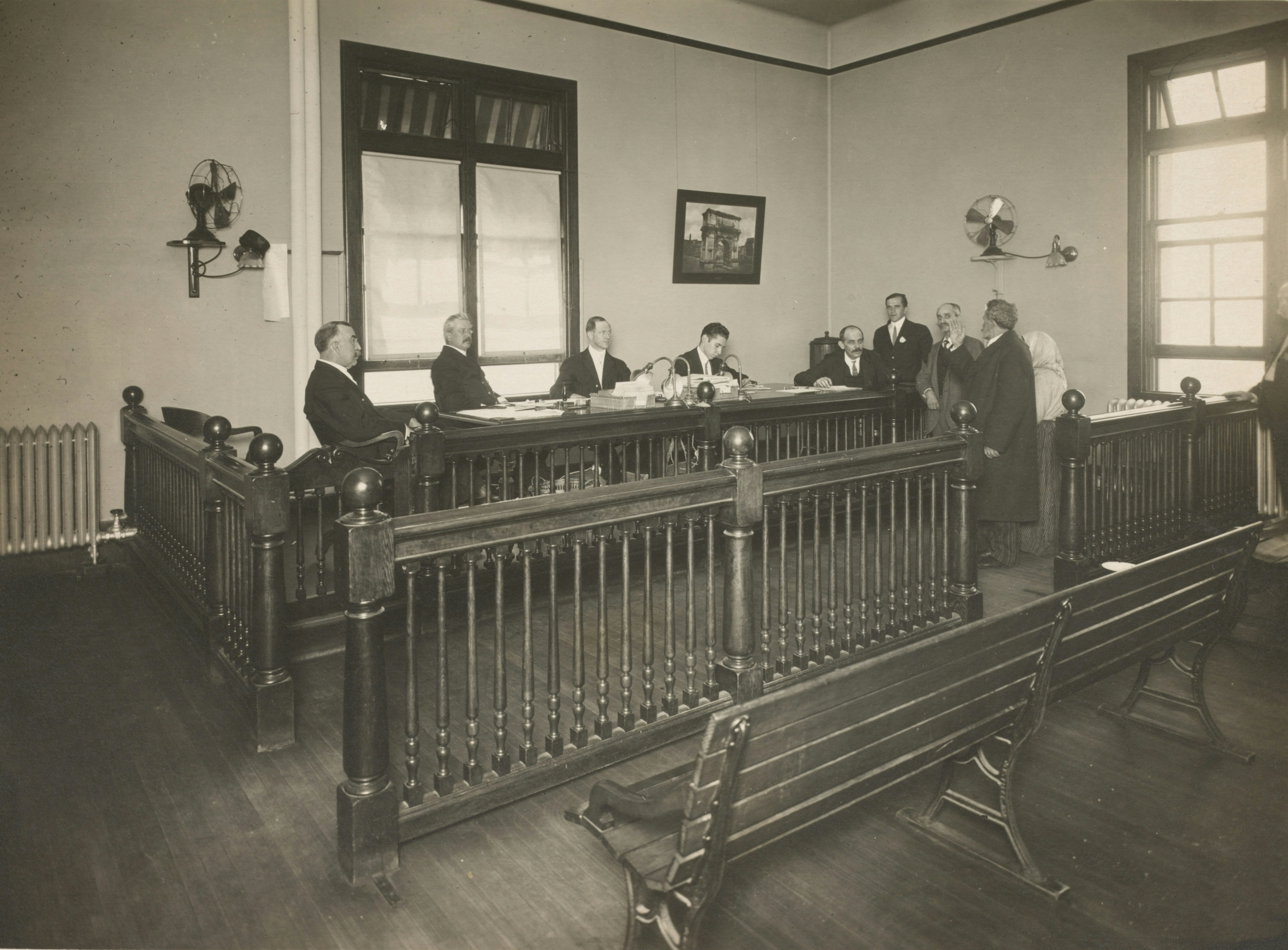 A bearded immigrant appearing before a board of inquiry, Ellis Island.